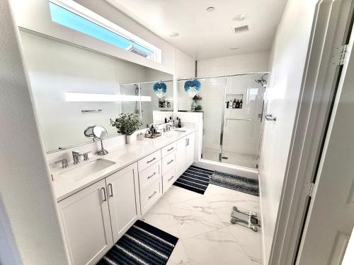a white bathroom with two sinks and a shower at Valencia Resort in Santa Clarita