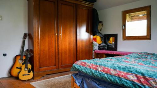 a bedroom with a bed and a guitar next to a cabinet at Sopotnica - Apartman na vodopadima in Prijepolje