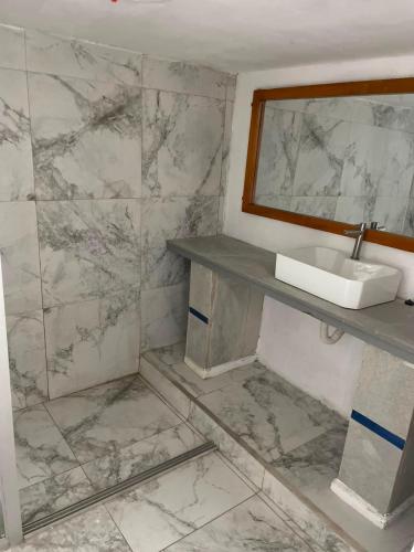 a bathroom with a sink and a marble wall at Hotel Cristian in Puyo