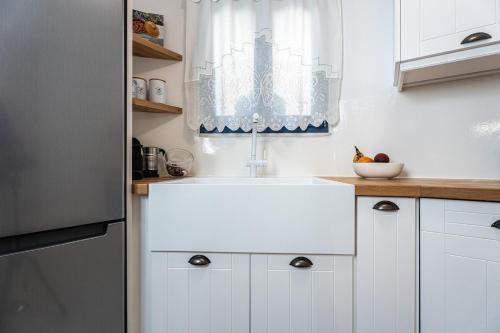 a white kitchen with a sink and a window at Terraegea Paros in Dhragoulás
