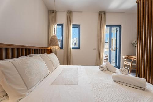 a bedroom with a large white bed with towels on it at Terraegea Paros in Dhragoulás