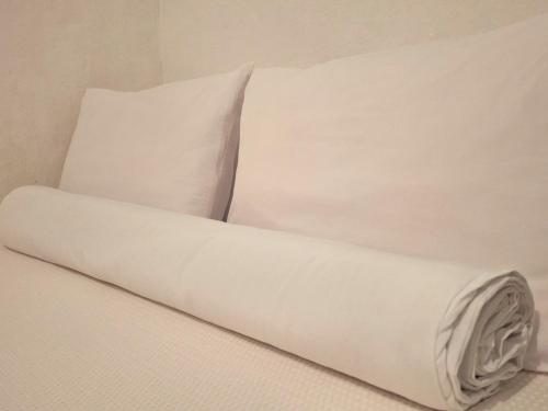 a bed with white sheets and a pillow at Pousada Caiçara Zen in Paraty