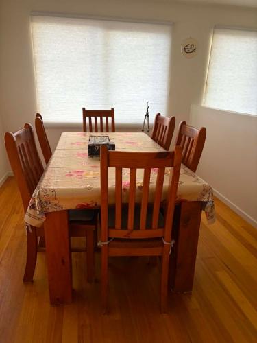 a dining room table with chairs and a wooden floor at Enkindled Haven in Moonah