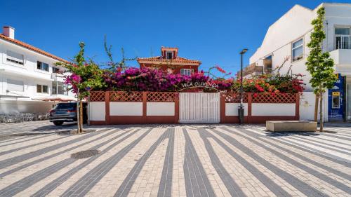 a fence with flowers on top of a building at Vila Olivença in Costa da Caparica