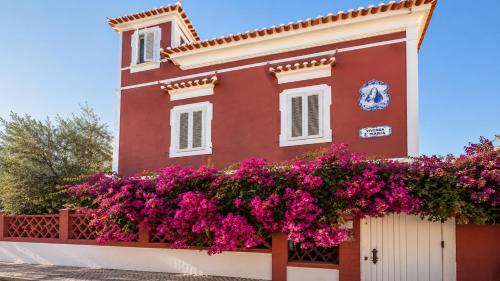a house with pink flowers on a fence at Vila Olivença in Costa da Caparica