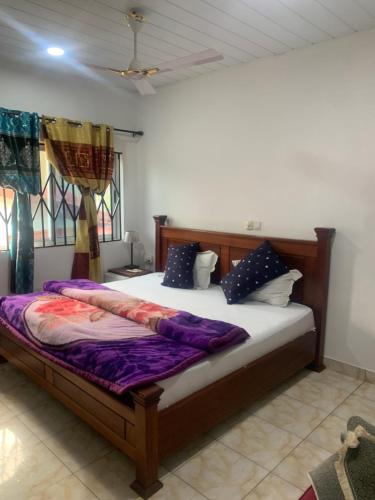 a bedroom with a large bed with purple sheets at Abronoma Guest House in Ogbojo