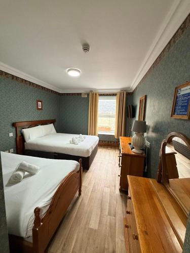 a bedroom with two beds and a table and a window at Imperial Lodge in Lisdoonvarna