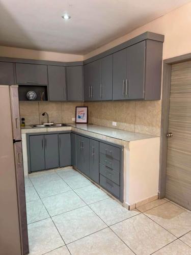 a kitchen with gray cabinets and a sink and a tile floor at Departamento #5 in San Carlos