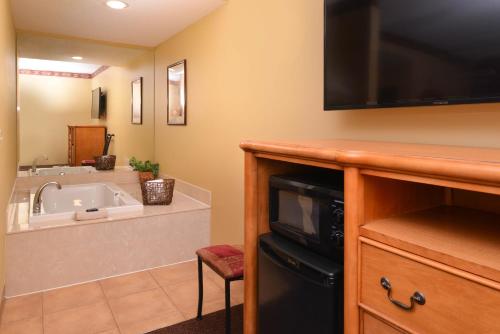 a bathroom with a sink and a tv on the wall at Country Hearth Inn & Suites Edwardsville in Edwardsville