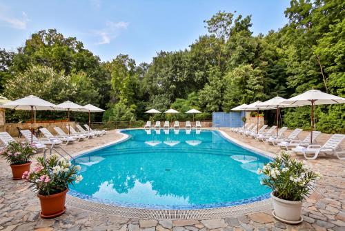 a swimming pool with chairs and umbrellas at Kamchia Park Hotel - All Inclusive in Golden Sands