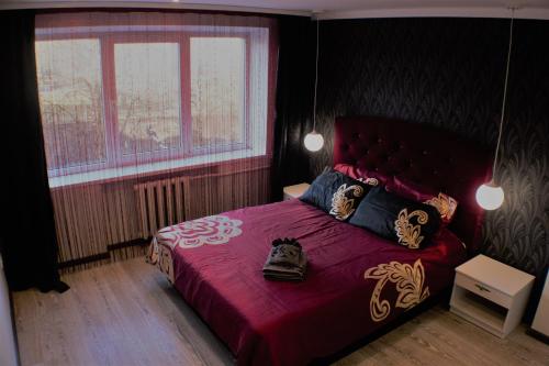 a bedroom with a bed with a red bedspread at Siauliai Apartments - Ežero in Šiauliai