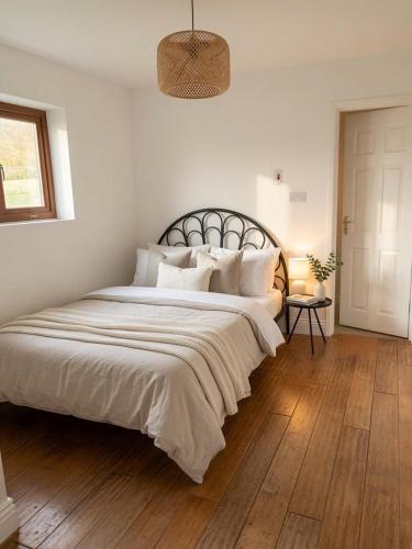 a white bedroom with a large bed with white pillows at Dunmore East Studio in Rathmoylan