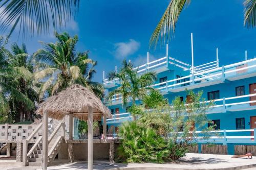 a hotel on the beach with palm trees at Charming Suite with WiFi AC Shared Pool Grill Area & Rooftop Deck in Caye Caulker