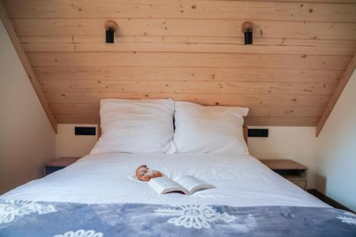 a bed with a book and a donut on it at Domek Za Dworem in Witów