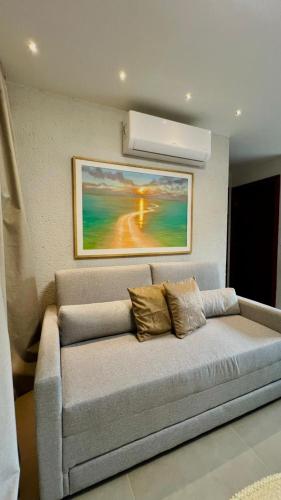 a couch in a living room with a painting on the wall at Villa Maui - Milagres in Passo de Camarajibe