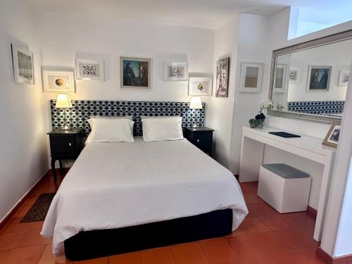 a bedroom with a large white bed and a desk at Santiago Oceanfront Living in Sesimbra