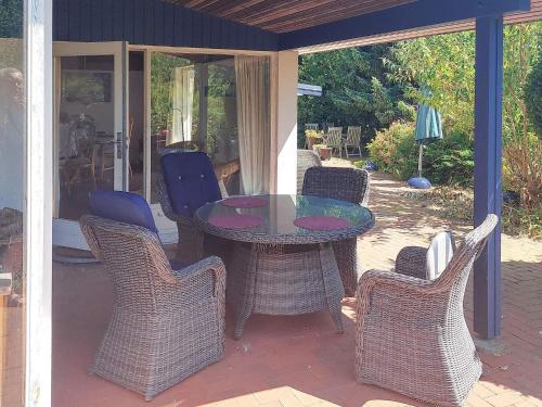 a patio with a glass table and wicker chairs at 4 star holiday home in Hundested in Hundested