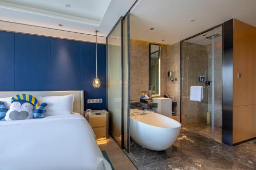 a bedroom with a bed and a tub and a bathroom at voco Xian ETDZ by IHG in Xi'an