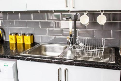 a kitchen sink with a dish drying rack next to it at Spacious Large Group House Near NEC and Airport in Birmingham