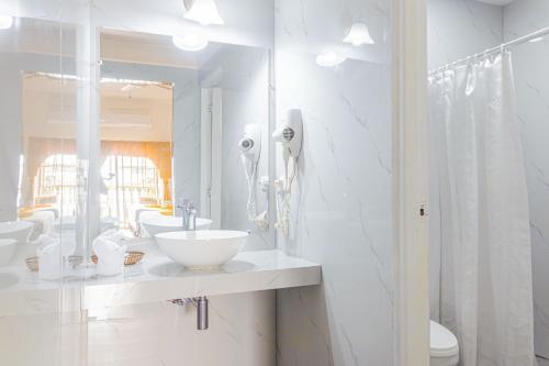 a white bathroom with two sinks and a mirror at Hotel Peten in Flores