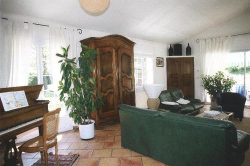 a living room with a green couch and a piano at Villa élégante à Céreste avec piscine privée et jacuzzi in Céreste