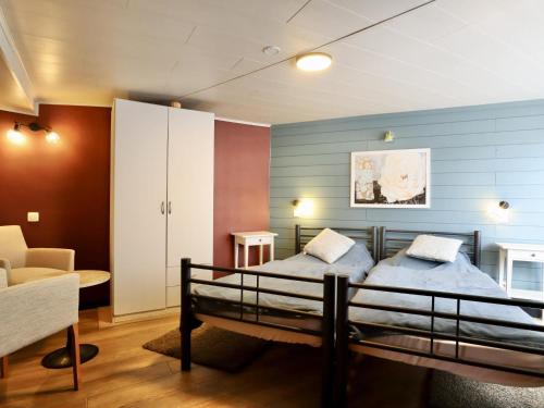a bedroom with two beds and a table and a chair at Sous les Hetres in Robertville