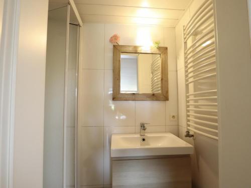 a white bathroom with a sink and a mirror at Sous les Hetres in Robertville