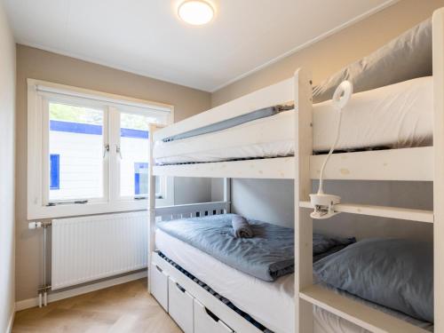 two bunk beds in a room with a window at Villa Fox in IJhorst