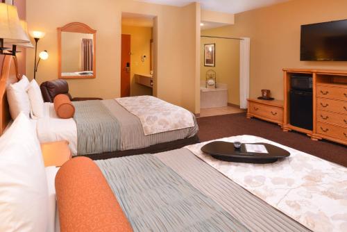 a hotel room with two beds and a flat screen tv at Country Hearth Inn & Suites Edwardsville in Edwardsville