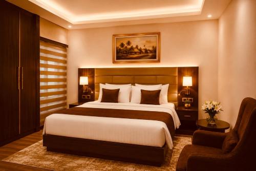 a bedroom with a large bed and a chair at E-Luxe Suites Hotel in Abuja