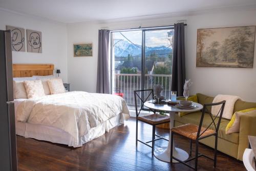 a bedroom with a bed and a table and a window at Wanderlust Studio Suite with Private Patio in Harrison Hot Springs