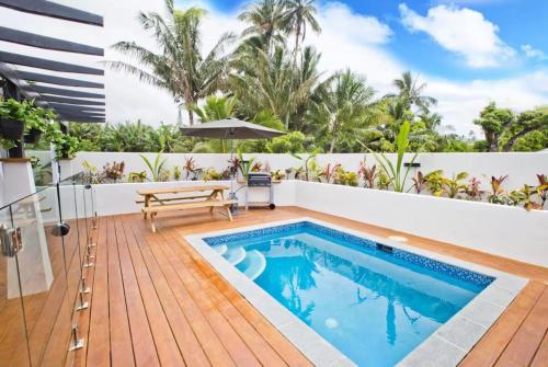 a swimming pool in the middle of a patio with a wooden deck at Konoha Central 9BR, 3 Pools, Sleeps 24 in Avarua
