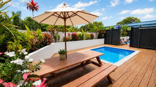 a patio with a wooden table and an umbrella at Konoha Central 9BR, 3 Pools, Sleeps 24 in Avarua