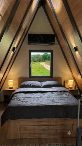 a bedroom with a large bed with a window at Breeze Cabin كوخ النسيم in Ilijaš