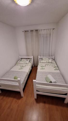 two beds in a room with white walls and wooden floors at Apartman Anita in Livno