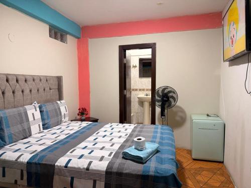 a bedroom with a bed with a blue and white blanket at Hostal Muchik in Chiclayo