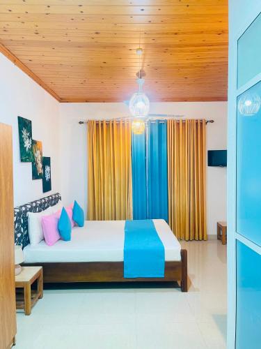 a bedroom with a bed with blue and yellow curtains at FEEL Villa in Kalutara