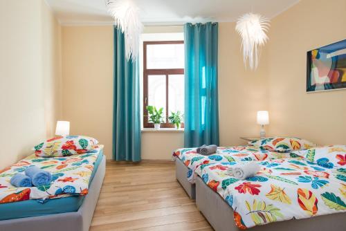 two beds in a bedroom with blue curtains and a window at Style4rent Apartament Kazimierz in Krak&oacute;w