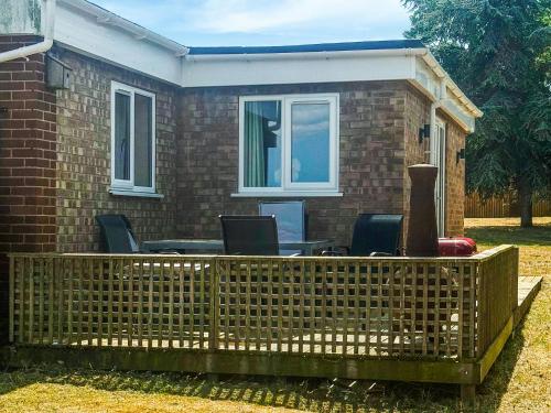 a fence with a table and chairs in front of a house at Jubilee Farm Cottage in Washingborough