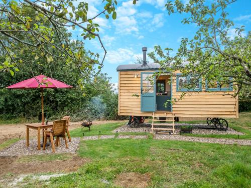 a tiny house with a table and an umbrella at Shepherd's Retreat in Ongar
