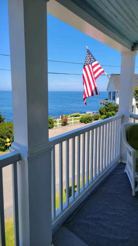 a porch with an american flag and the ocean at Oceanfront Classic Maine Cottage In Close Walking Distance To Beaches! in York