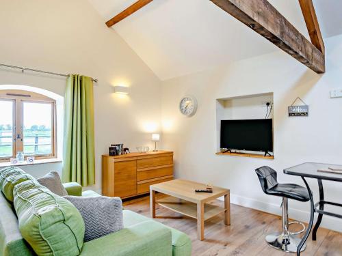 a living room with a green couch and a tv at The Dairy - Uk10957 in Burlton