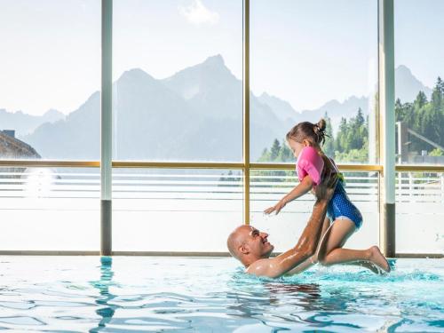 a little girl playing with a man in the swimming pool at Landal Brandnertal in Bürserberg