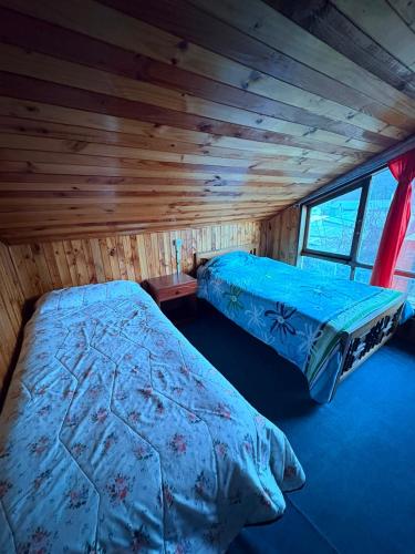 a bedroom with a bed in a log cabin at Casa familiar Queule in Queule