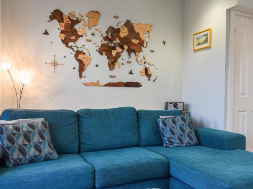 a blue couch in a living room with a world map on the wall at Coed Faen in Saint Helens