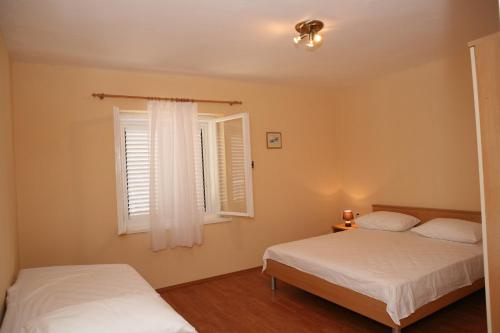 sypialnia z 2 łóżkami i oknem w obiekcie Apartments Radić w Trogirze