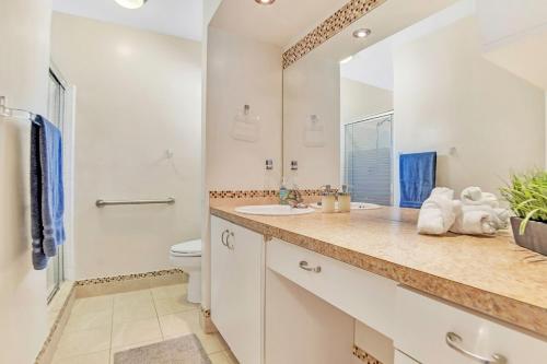 a bathroom with a sink and a toilet and a mirror at New Casa Eva Turfed Pool 5Br in Hallandale Beach