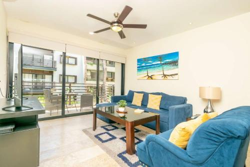 a living room with a blue couch and a table at 2Br Condo W Rooftop Pool & Backyard in Playa del Carmen