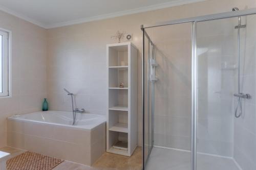a white bathroom with a shower and a bath tub at Villa Eldomar Heated Pool in Estreito da Calheta