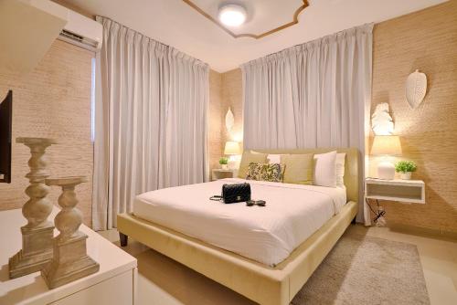 a bedroom with a large white bed with a bag on it at The-Comfty-Spot Experience Sd Wifi in Santo Domingo